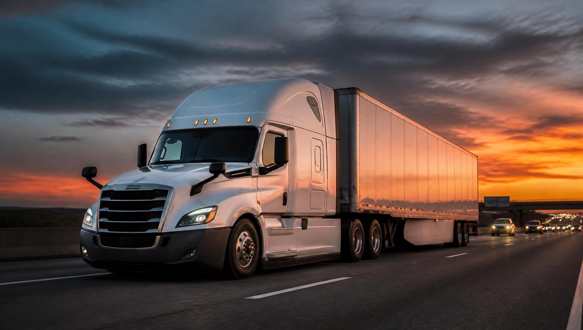 Modern semi truck pulling a commercial freight trailer on an American interstate highway at dusk